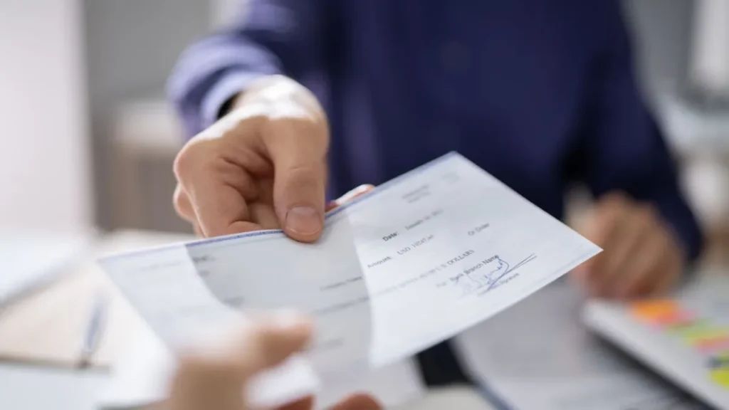Cheque de pago de nómina siendo cambiado en una ventanilla